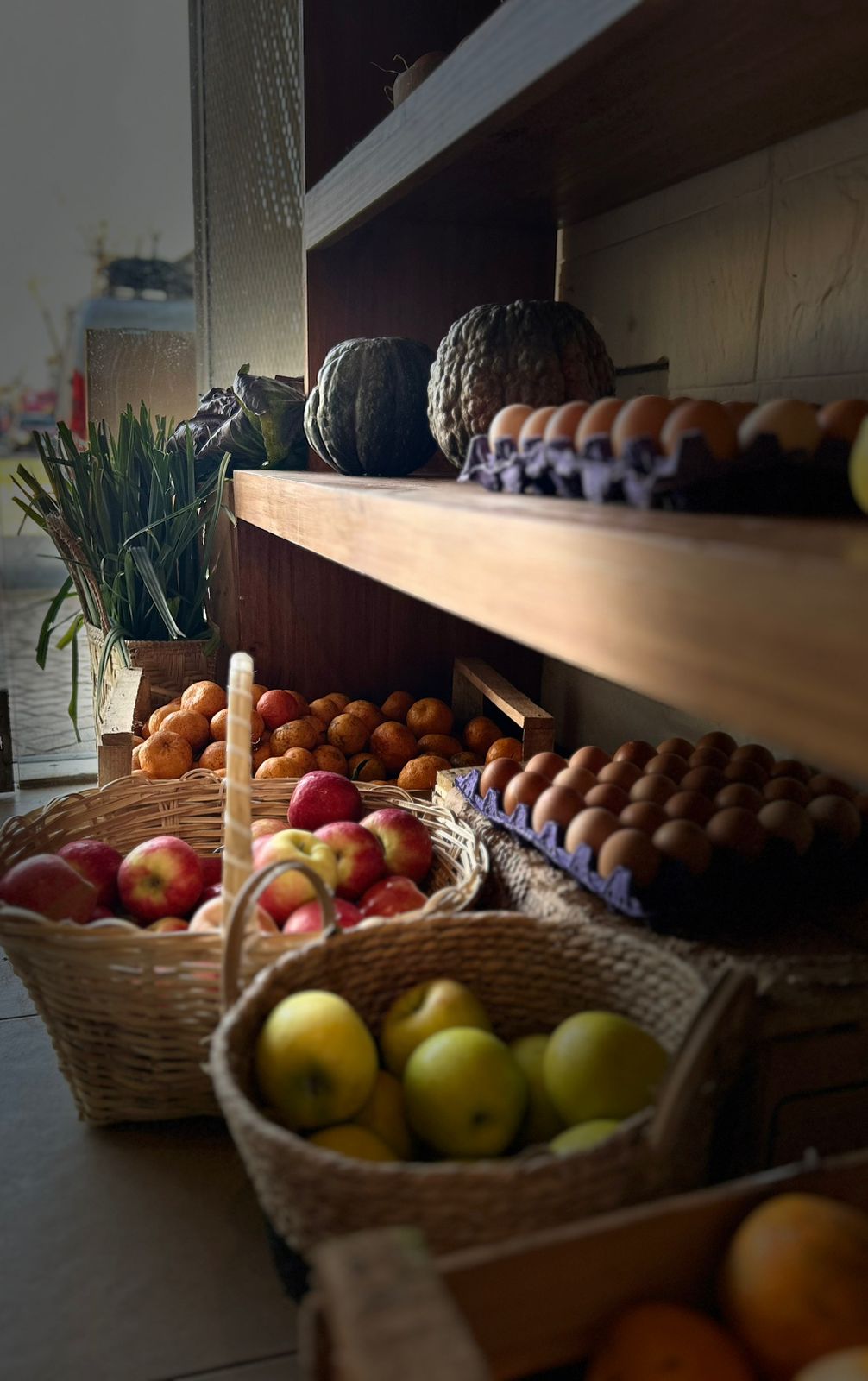 Canastos de manzanas, huevos y zapallos en la estantería del local